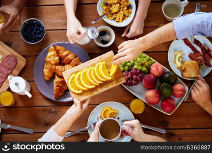 food, eating and family concept - group of people having breakfast and sharing orange at table. group of people having breakfast at table