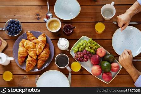 food, eating and family concept - hands of people having breakfast at table. hands of man having breakfast at table with food