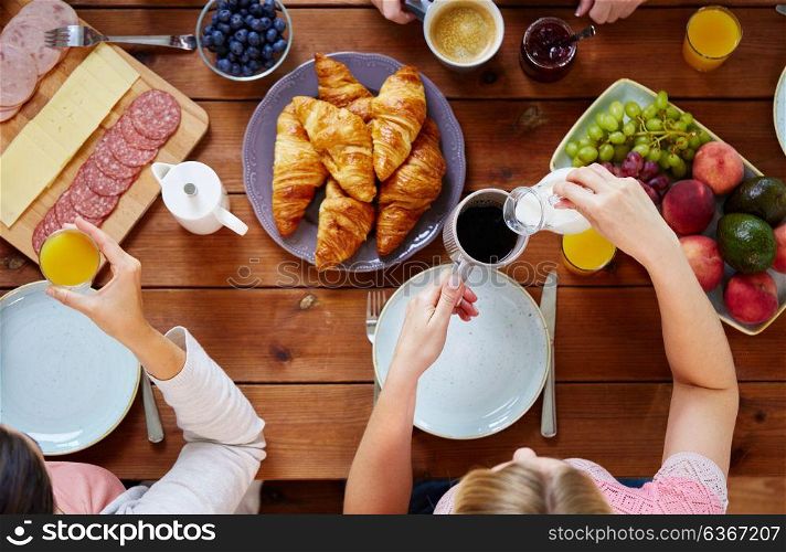 food, eating and family concept - women having breakfast and sitting at table. women having breakfast at table