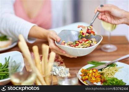 food, eating and leisure concept - people with salad having dinner. people eating salad at table with food