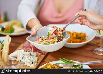 food, eating and leisure concept - people with salad having dinner. people eating salad at table with food