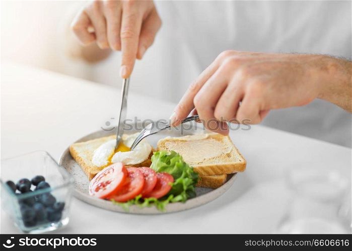 food, eating and people concept - close up of man having toasts with poached egg and vegetables for breakfast. close up of man having toasts for breakfast