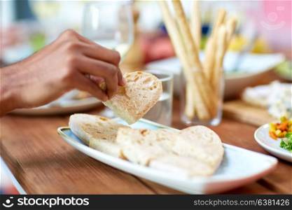 food, eating and people concept - hand taking piece of bread from plate. hand taking piece of bread from plate