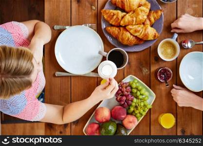 food, eating and people concept - two woman with cream and coffee having breakfast and sitting at table. woman with cream and coffee having breakfast