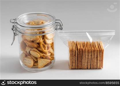 food, eating and snacks concept - close up of salted cookies or crackers in jar and zip lock bag on white background. salted cookies or crackers in jar and zip lock bag