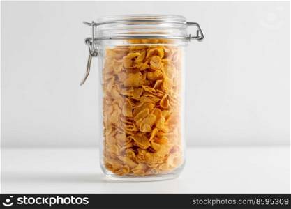 food, eating and storage concept - close up of jar with corn flakes on white background. close up of jar with corn flakes on white table