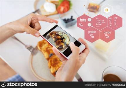 food , eating and technology concept - hands with pancakes on smartphone screen over nutritional value chart. hands with food on smartphone screen