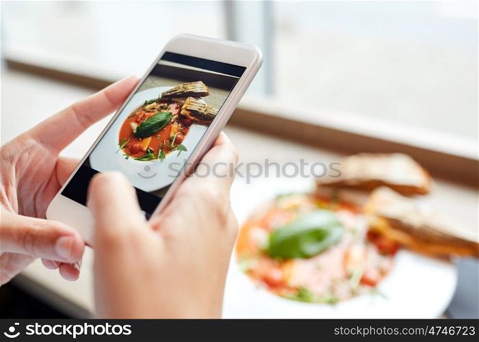 food, eating, technology, culinary and people concept - woman hands with gazpacho soup photo on smartphone screen at restaurant