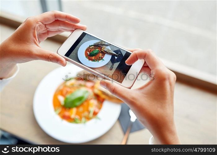 food, eating, technology, culinary and people concept - woman hands with smartphone photographing gazpacho soup at restaurant