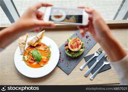 food, eating, technology, culinary and people concept - woman hands with smartphone photographing gazpacho soup and salad at restaurant