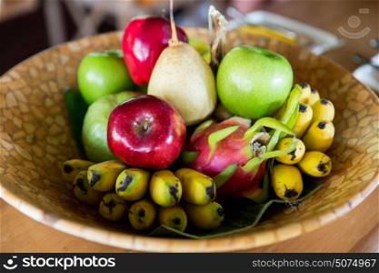 food, eco, bio and summer holidays concept - still life with exotic tropical fruits in bowl. still life with exotic tropical fruits in bowl