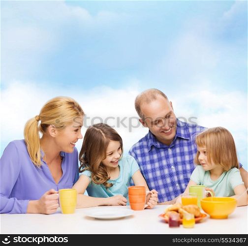 food, family, children, hapiness and people concept - happy family with two kids having breakfast at home
