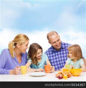 food, family, children, hapiness and people concept - happy family with two kids having breakfast at home