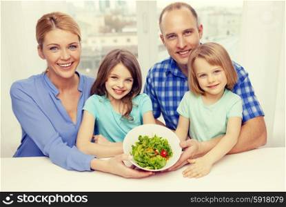 food, family, children, happiness and people concept - happy family with two kids with salad at home