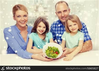 food, family, children, happiness and people concept - happy family with two kids showing salad in bowl at home