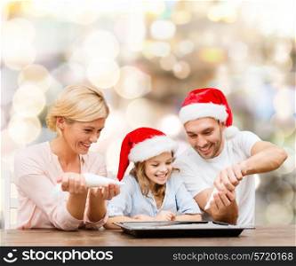 food, family, christmas, happiness and people concept - smiling family in santa helper hats with glaze and pan cooking over lights background