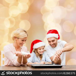 food, family, christmas, happiness and people concept - smiling family in santa helper hats with glaze and pan cooking over beige lights background