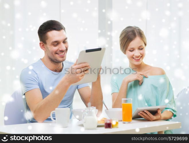 food, family, people and technology concept - smiling couple with tablet pc computers reading news and having breakfast at home