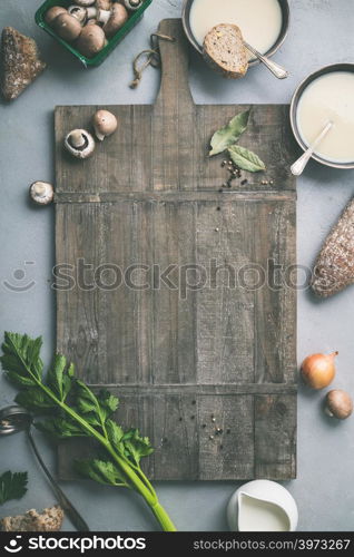 Food frame. Bowls of homemade mushroom soup and ingredients on grey concrete background, top view, space for text