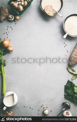 Food frame. Bowls of homemade mushroom soup and ingredients on grey concrete background, top view, space for text