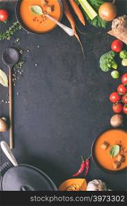 Food frame. Bowls of homemade tomato soup and ingredients on rustic background, top view, space for text