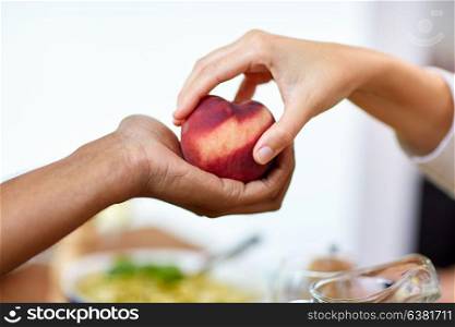 food, fruit and healthy eating concept - multiracial couple hands with peach. multiracial couple hands with peach