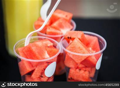 food, fruits and eating concept - close up of chopped watermelon in plastic cups