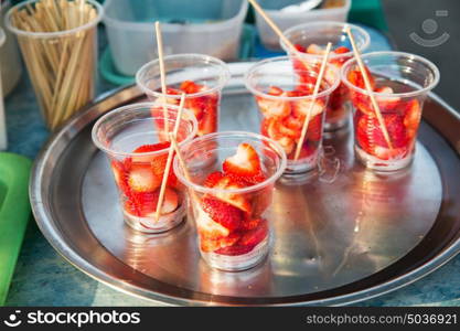 food, fruits and eating concept - strawberry in plastic cups at street market or party. strawberry in plastic cups at street market