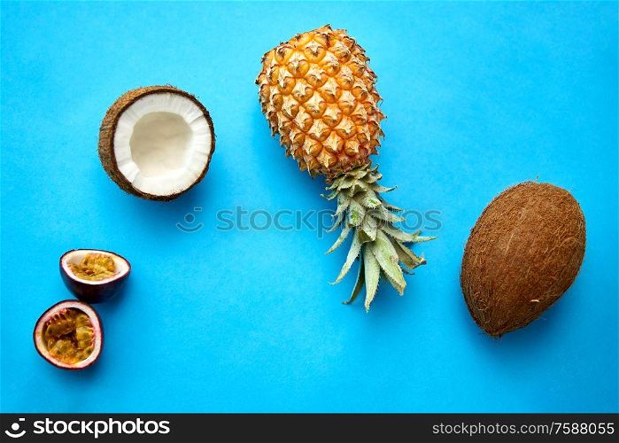 food, fruits and healthy eating concept - pineapple, passion fruit and coconut on blue background. pineapple, passion fruit and coconut on blue