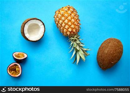 food, fruits and healthy eating concept - pineapple, passion fruit and coconut on blue background. pineapple, passion fruit and coconut on blue