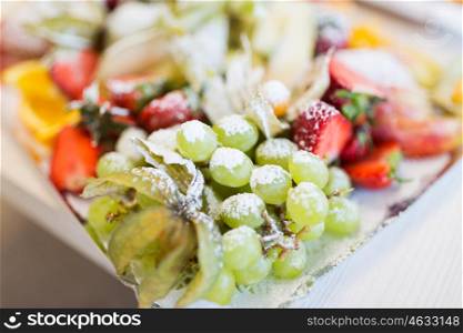 food, fruits, dessert and holidays concept - close up of dish with sugared grapes