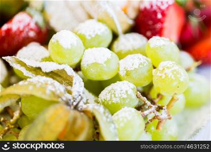 food, fruits, dessert and summer concept - close up of dish with sugared grapes