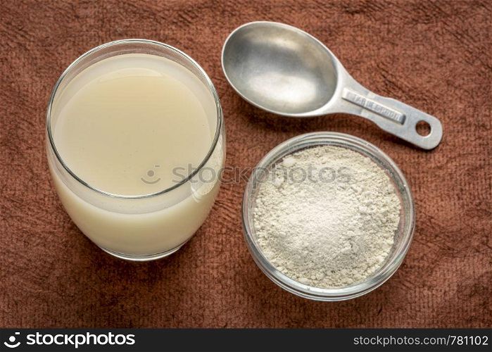 food grade diatomaceous earth supplement - powder and in a glass of water with measuring scoop