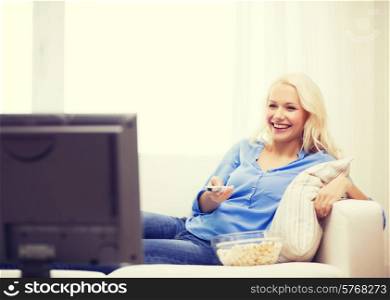 food, happiness and people concept - smiling young girl with popcorn watching movie at home