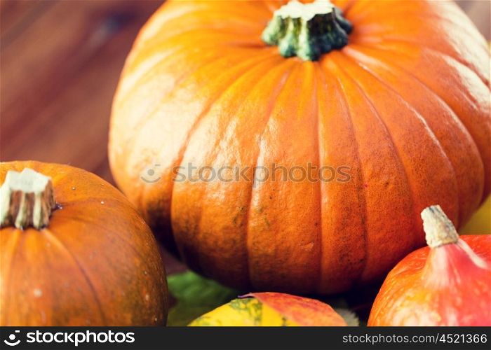 food, harvest, season and autumn concept - close up of pumpkins on wooden table at home