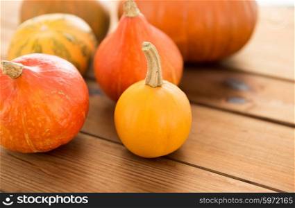 food, harvest, season and autumn concept - close up of pumpkins on wooden table at home