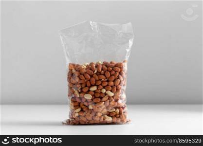 food, healthy eating and diet concept - bag with raw peanuts on white background. close up of bag with peanuts on white table