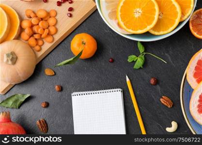 food, healthy eating and diet concept - close up of notebook, fruits and vegetables on slate table top. close up of notebook, fruits and vegetables