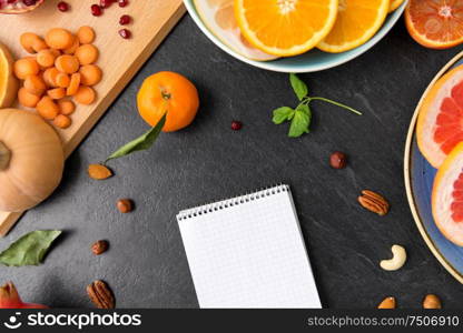 food, healthy eating and diet concept - close up of notebook, fruits and vegetables on slate table top. close up of notebook, fruits and vegetables