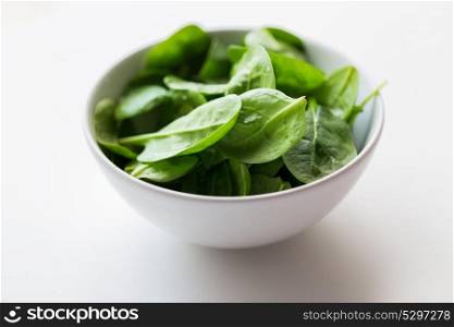 food, healthy eating and diet concept - close up of spinach leaves in white bowl. close up of spinach leaves in white bowl