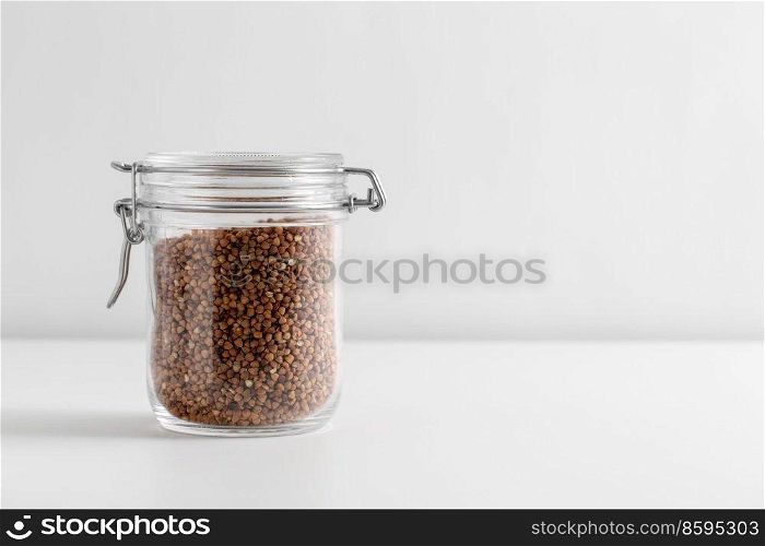 food, healthy eating and diet concept - jar with buckwheat on white background. close up of jar with buckwheat on white table