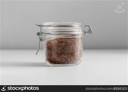 food, healthy eating and diet concept - jar with flax seeds on white background. close up of jar with flax seeds on white table