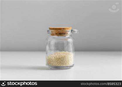 food, healthy eating and diet concept - jar with sesame seeds on white background. close up of jar with sesame seeds on white table