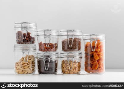 food, healthy eating and diet concept - jars with dried fruits and seeds nuts on white background. jars with dried fruits, cereals and nuts on table