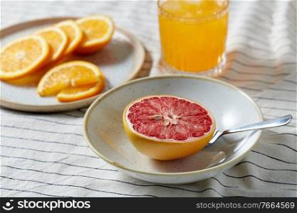 food, healthy eating and fruits concept - still life of grapefruit, sliced orange and glass of juice over drapery. grapefruit, sliced orange and glass of juice