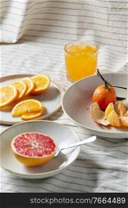 food, healthy eating and fruits concept - still life of mandarin, grapefruit and glass of orange juice over drapery. mandarin, grapefruit and glass of orange juice