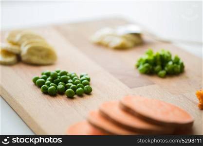 food, healthy eating and nutrition concept - pile of peas and other vegetables on wooden board. peas and other vegetables on wooden board