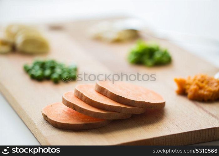 food, healthy eating and nutrition concept - sliced pumpkin and other vegetables on wooden board. sliced pumpkin on wooden board