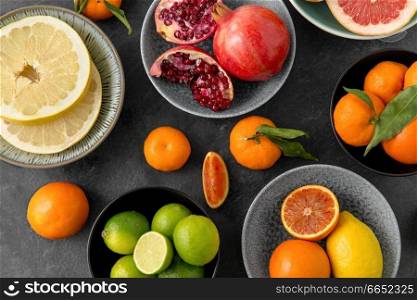 food, healthy eating and vegetarian concept - close up of citrus fruits in bowls on stone table. close up of citrus in bowls fruits on stone table