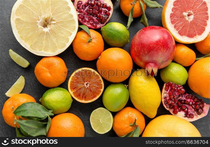 food, healthy eating and vegetarian concept - close up of citrus fruits on stone table. close up of citrus fruits on stone table